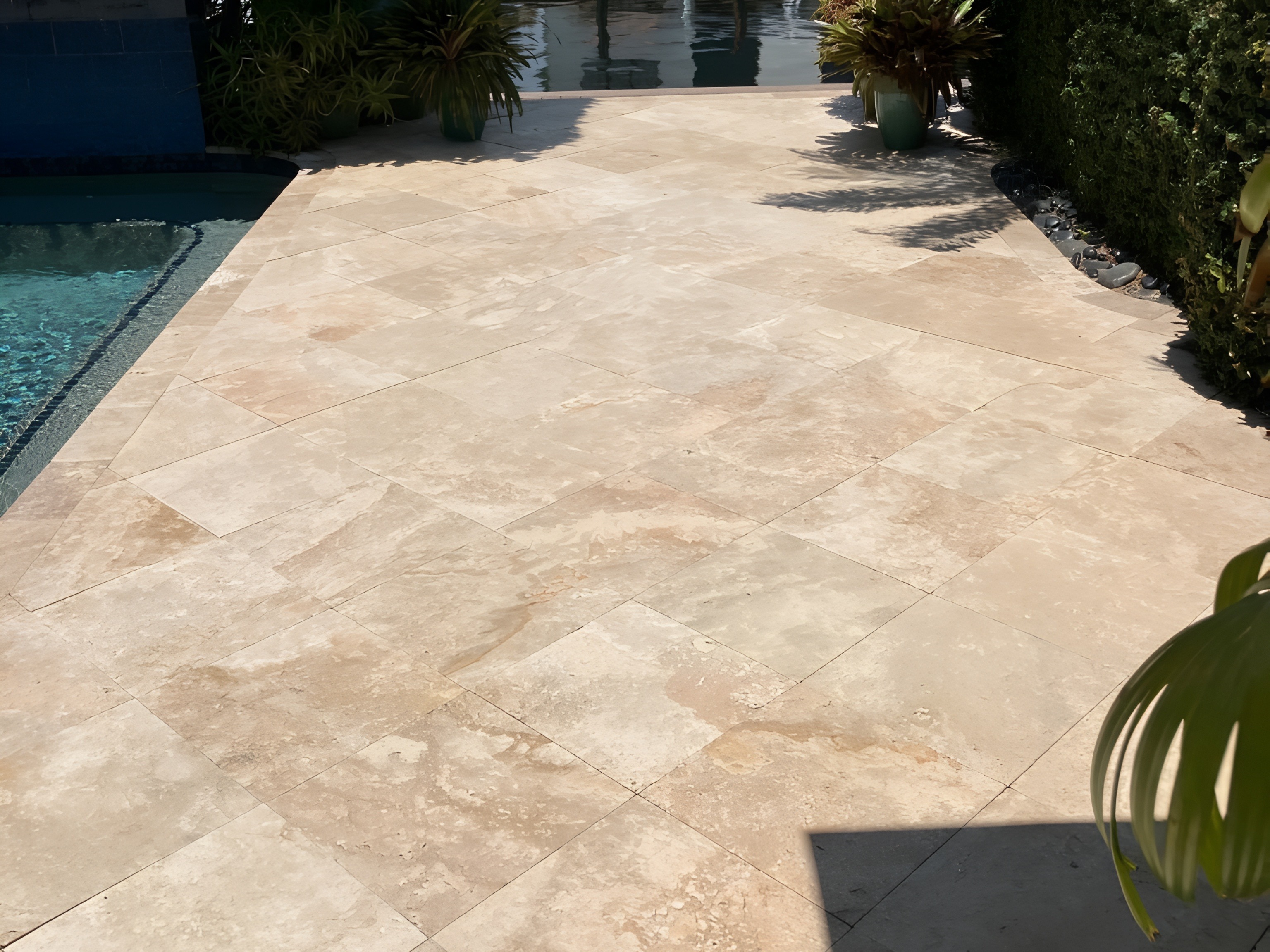 Luxury travertine pool deck beside a South Florida canal with tropical landscaping — Contour Marine