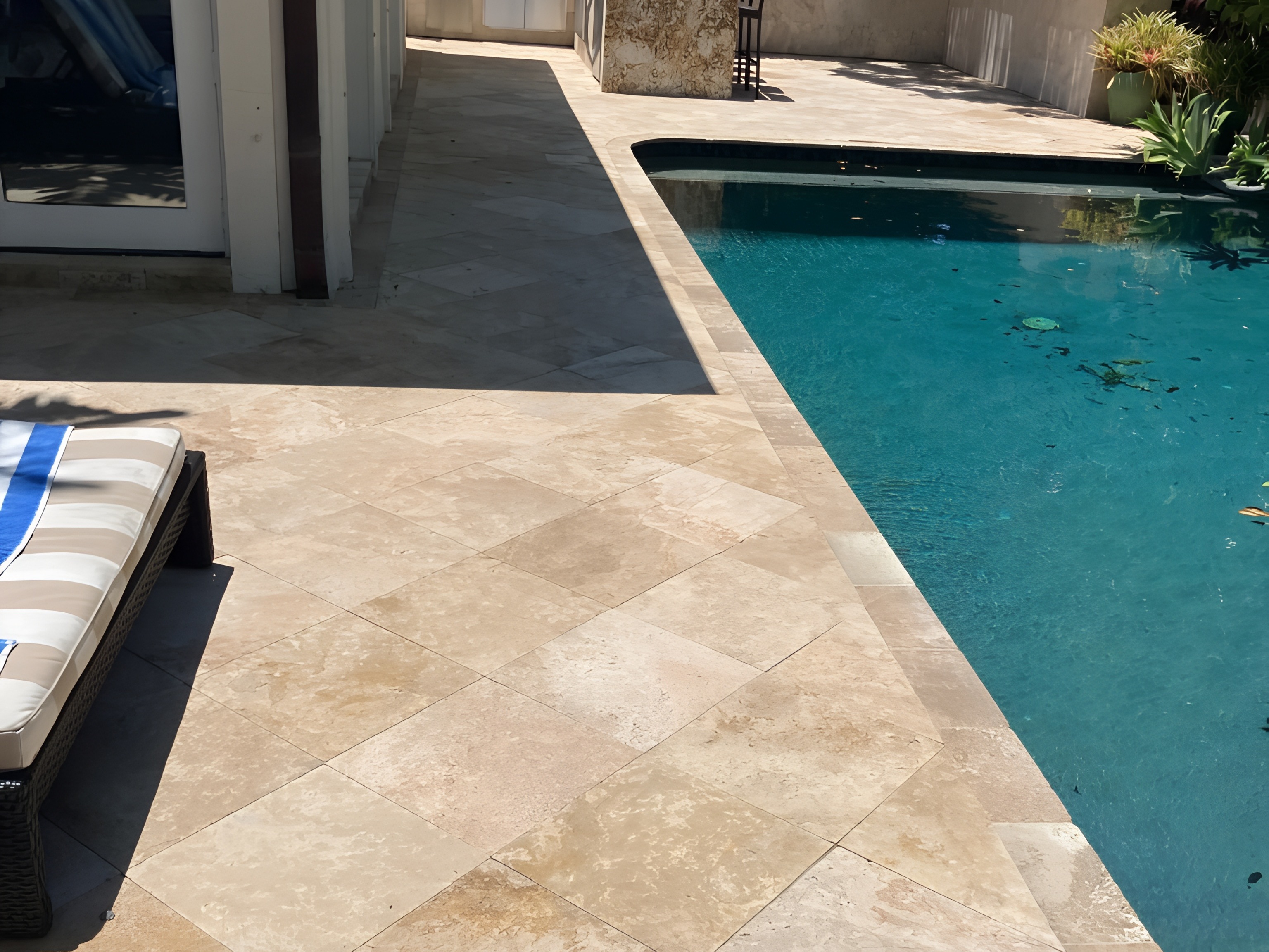 Travertine pool deck with outdoor kitchen and blue pool water — South Florida by Contour Marine