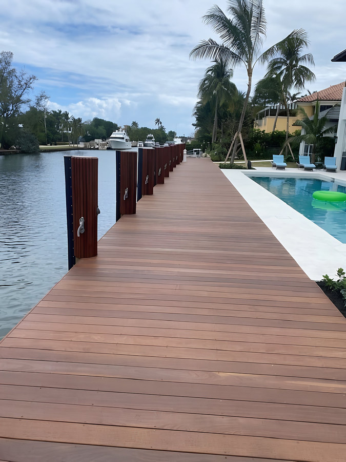 Long Ipe hardwood dock alongside luxury pool and palm trees on South Florida canal — Contour Marine