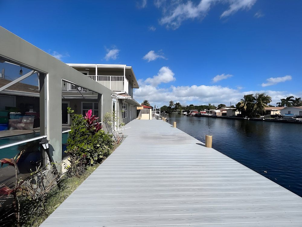 Long grey composite dock alongside waterfront home on South Florida canal