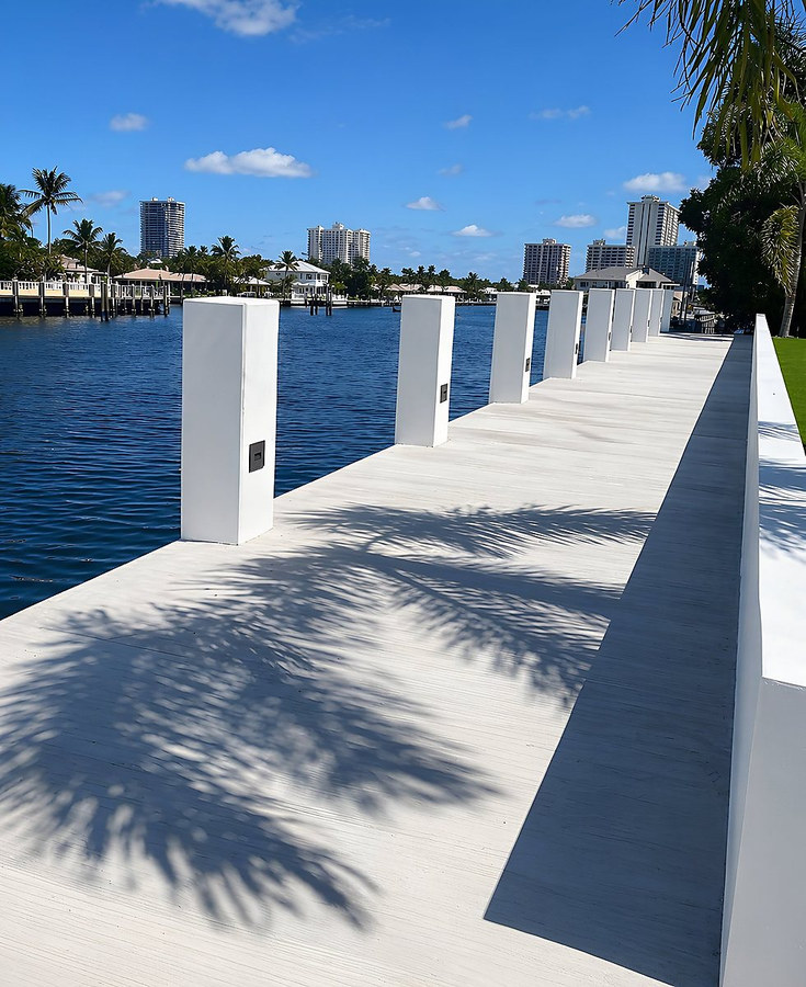 Modern dock with white square posts extending over blue water — South Florida by Contour Marine